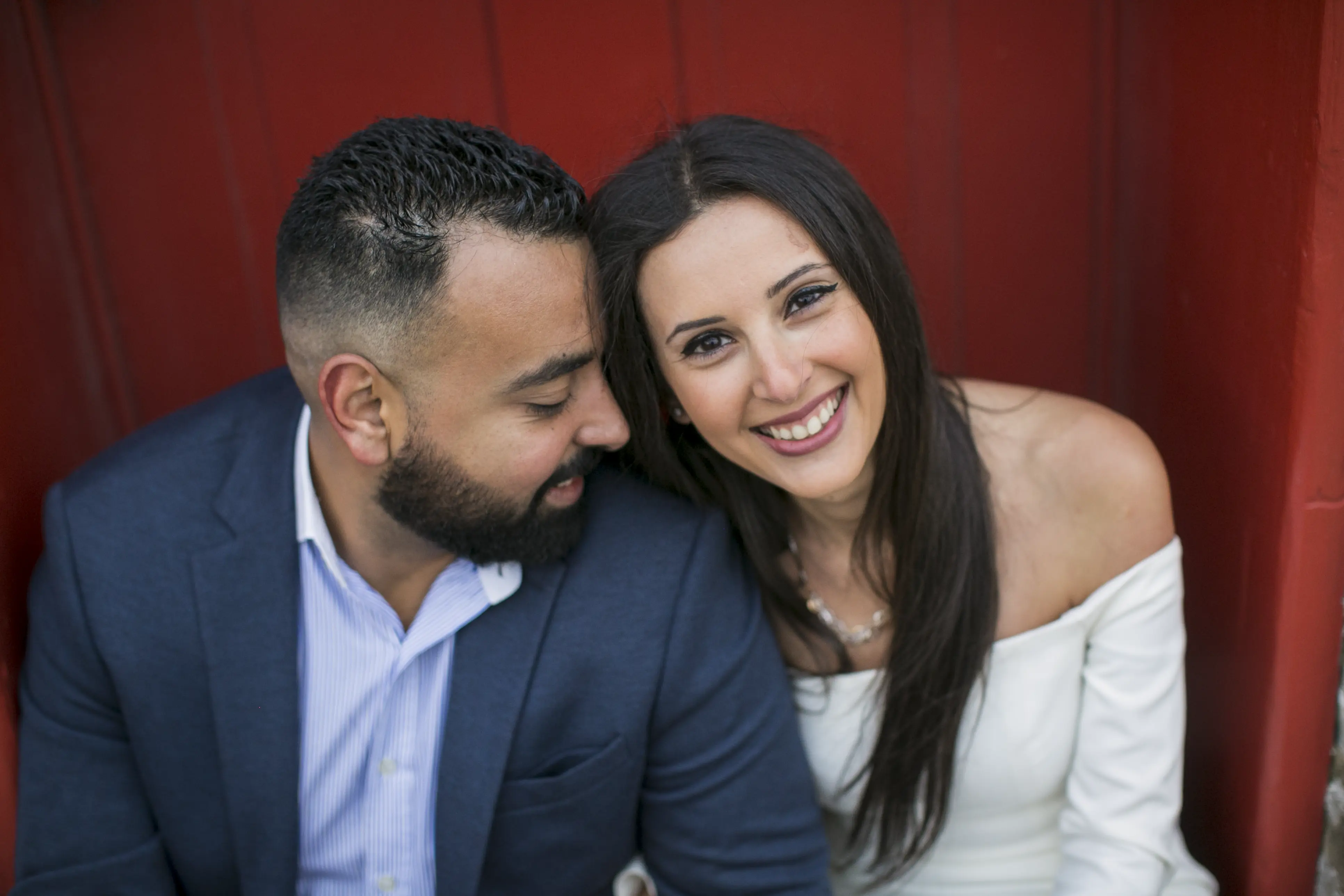 An engaged couple posing in front of a red door
